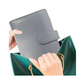 Gray Budget Binder with snap closure being placed into a green handbag by a person's hands